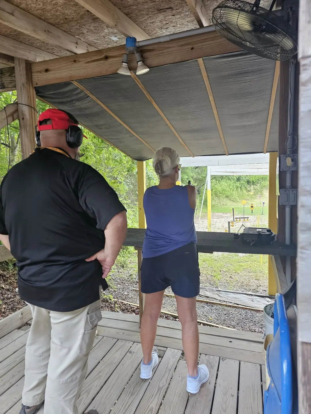 Member coaching a shooter at the covered pistol bench